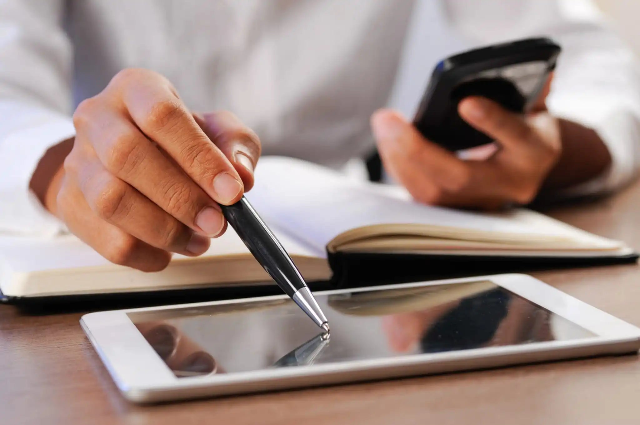 Professionista che lavora multitasking tra tablet, smartphone e appunti