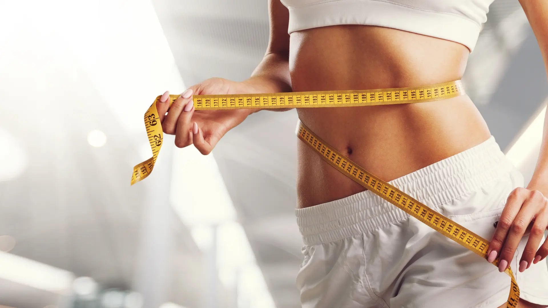 Donna che misura la circonferenza vita con un metro da sarta.