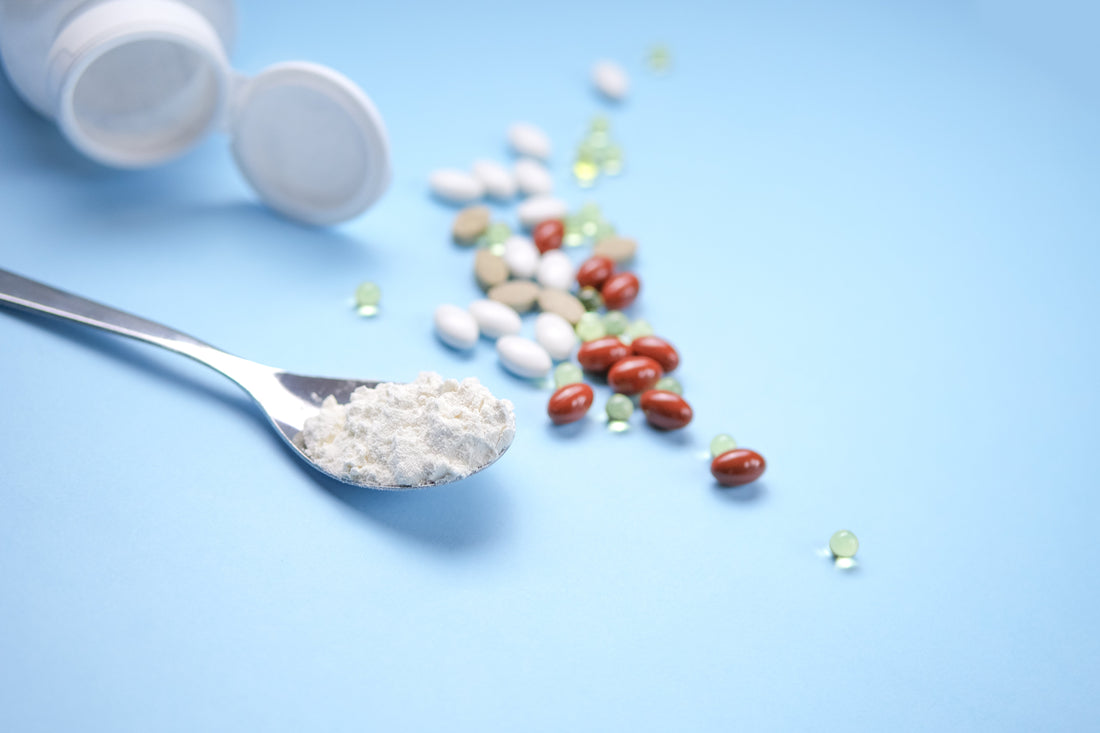 Integratori alimentari e polveri nutraceutiche con capsule e compresse su sfondo azzurro per salute, benessere e supplementazione.