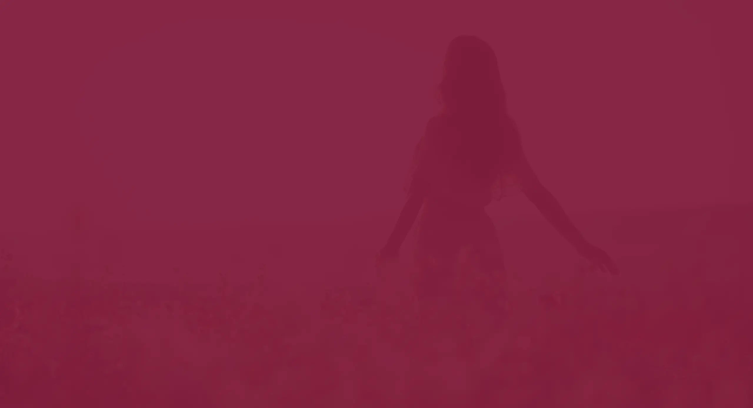 Donna che cammina tra i fiori in un paesaggio naturale, in un momento di pace e libertà con filtro bordeaux